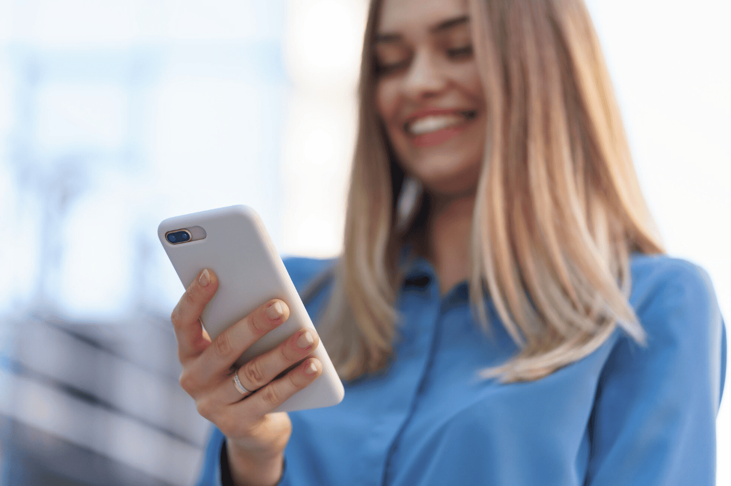 Ragazza sorridente usa lo smartphone all’aperto