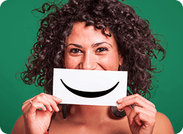 Donna con cartello sorridente, testo: ogni anno regaliamo il sorriso a migliaia di tabaccai in tutta Italia